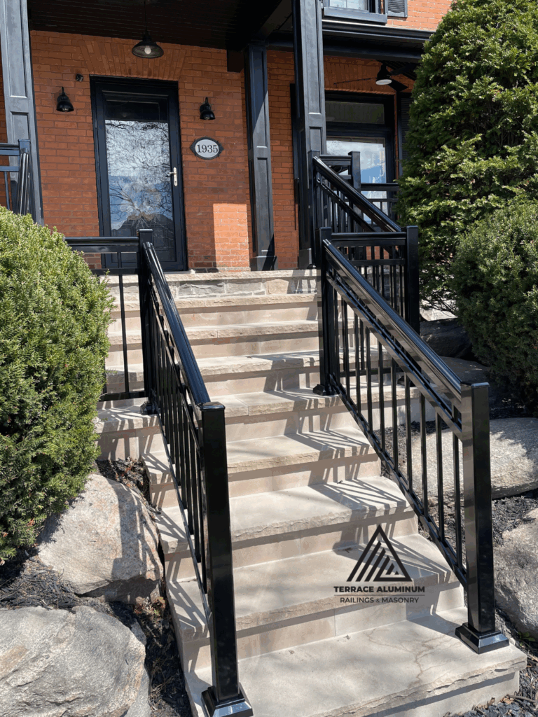 Custom Oakville porch with flagstone base and black aluminum railing design. Title:
