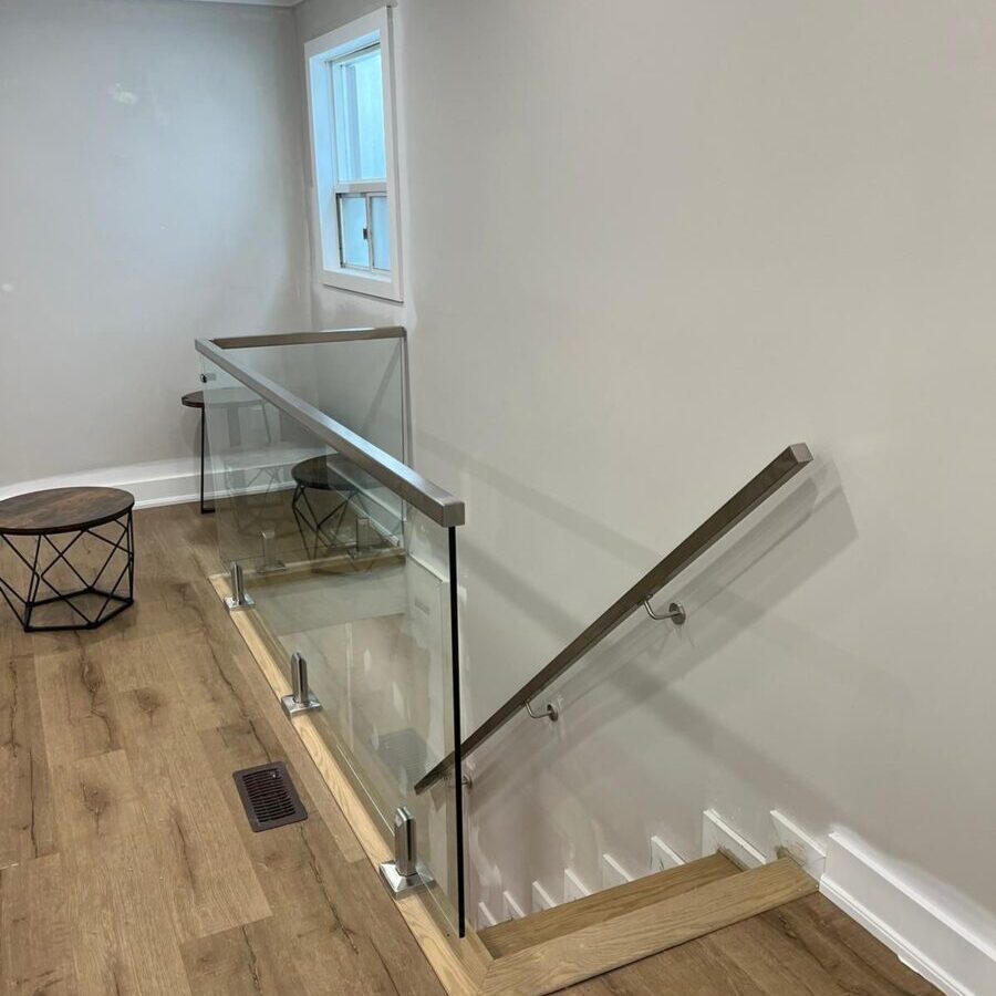 Interior glass railing with brushed stainless hardware and clear 12mm tempered glass panels installed in a Toronto home.