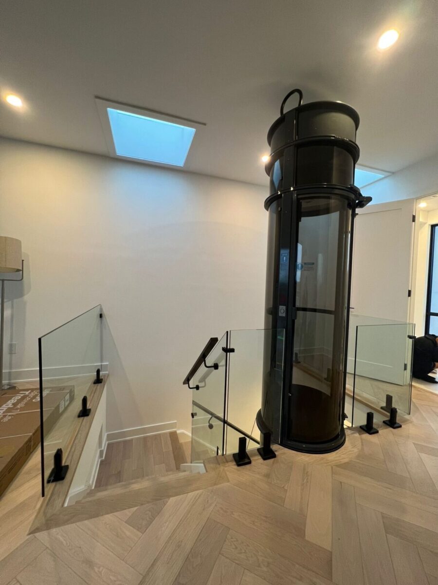 Frameless interior glass railing surrounding a glass elevator with 12mm tempered glass panels inside a modern Toronto home.