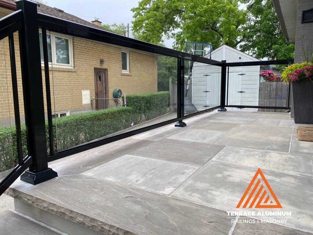 Aluminum framed clear glass railing installed on a front porch in Toronto by Terrace Aluminum Railings & Masonry.

