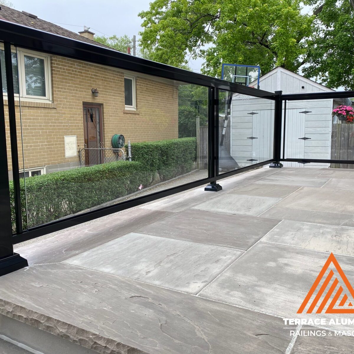 Aluminum framed clear glass railing installed on a front porch in Toronto by Terrace Aluminum Railings & Masonry.