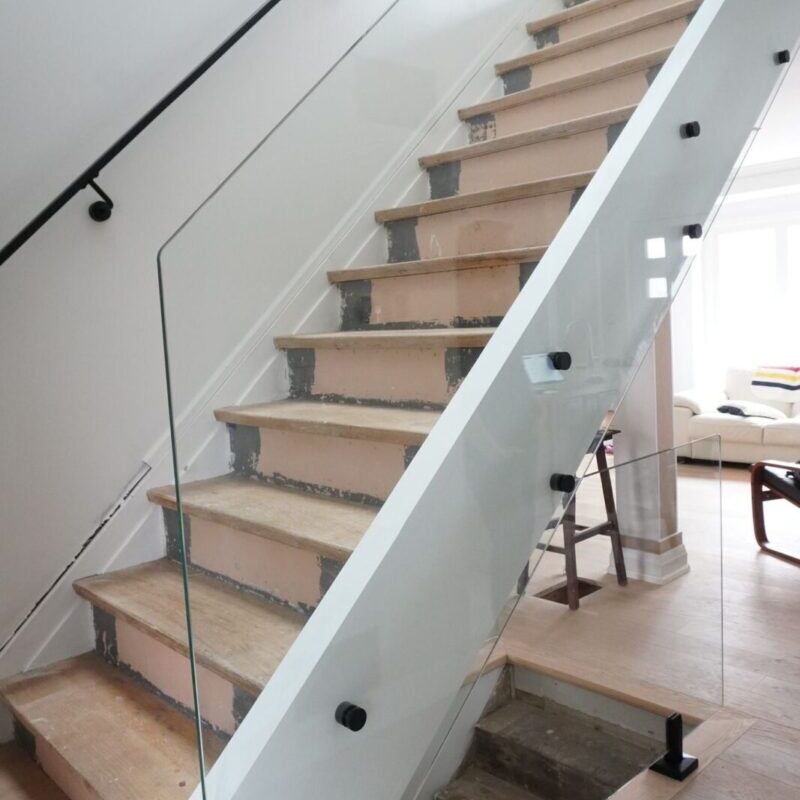 Interior glass railing with aluminum handrail and clear tempered glass panels installed in a modern Toronto home.