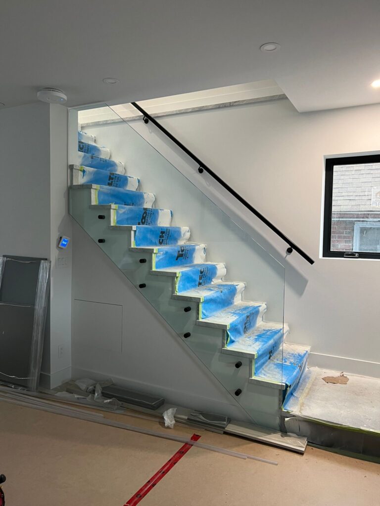 Modern interior glass staircase railing with frameless 12mm tempered glass panels in a Toronto home.