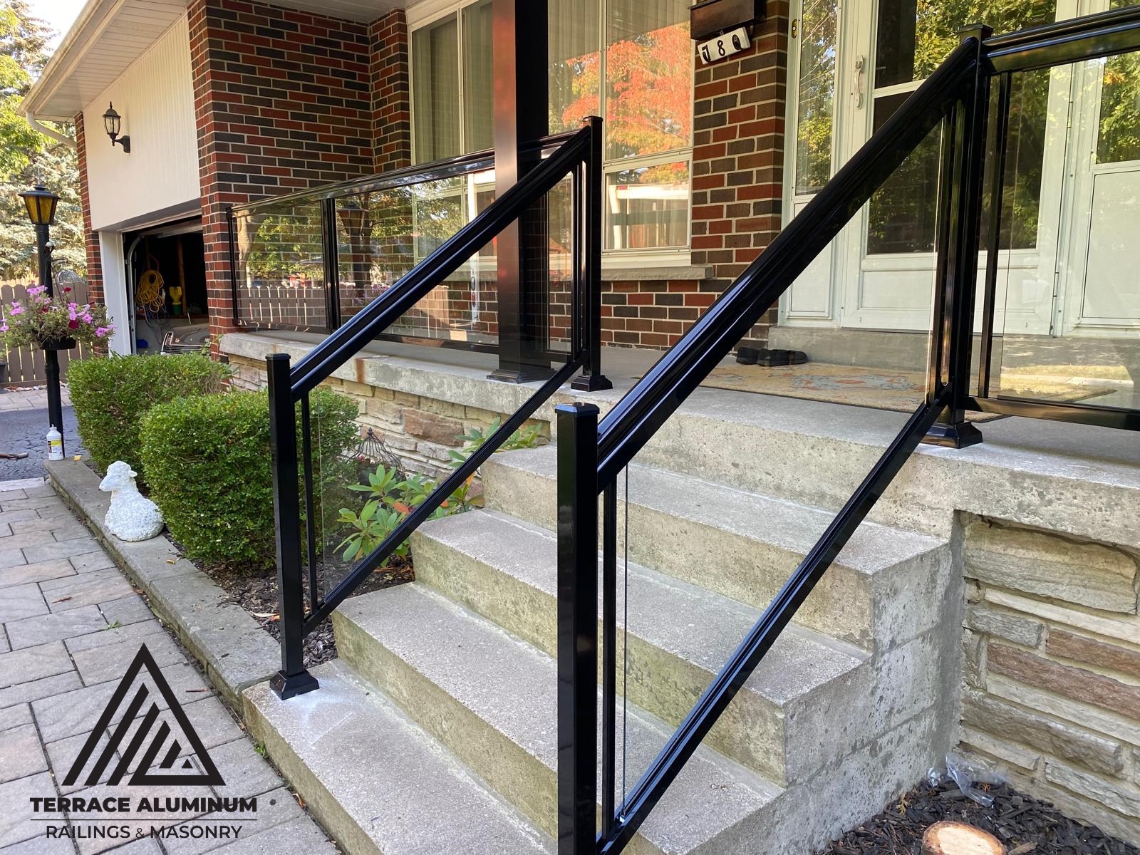 alt="Aluminum glass railing on a porch in Toronto installed by Terrace Aluminum Railings, featuring clear tempered glass panels and powder-coated aluminum posts for a sleek modern appearance."