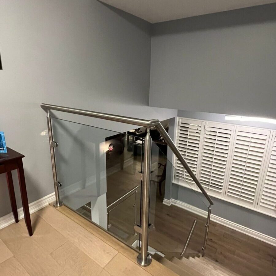 Interior glass railing with stainless steel posts, matching handrail, and 10mm tempered glass panels installed in a modern Toronto home.