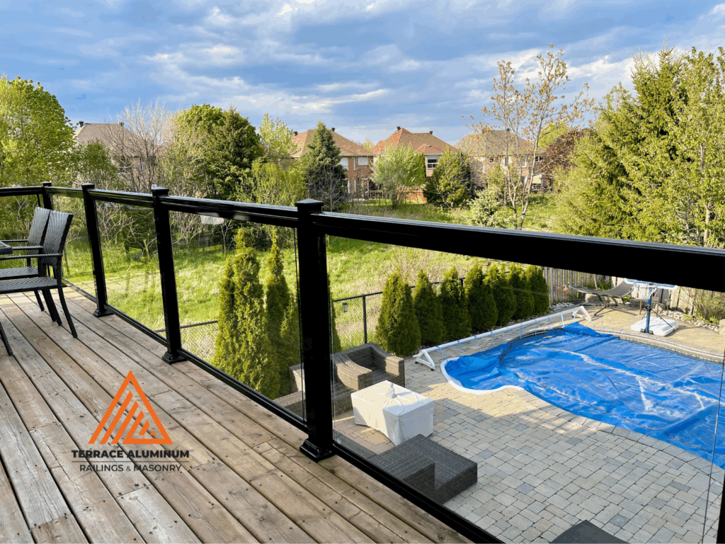 Tempered glass deck railing with black aluminum frame overlooking backyard and pool in Toronto – Terrace Aluminum Railings & Masonry