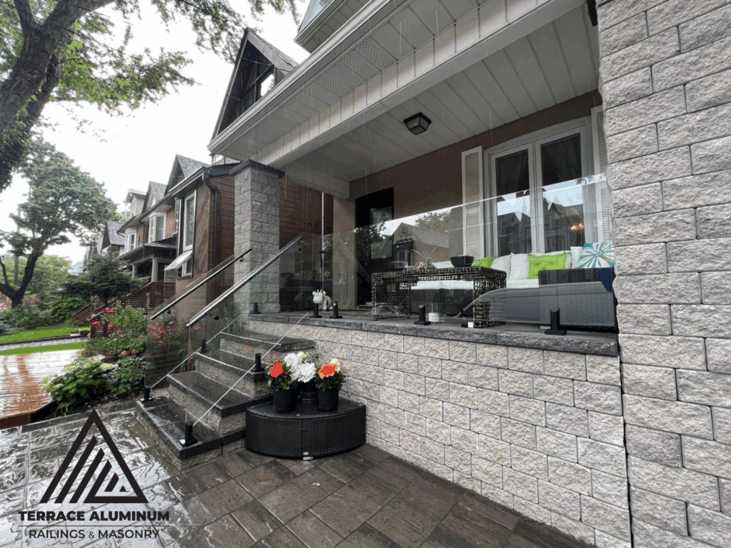 alt="Frameless glass railing Toronto installed by Terrace Aluminum Railings featuring 12mm tempered glass and stainless steel spigots for a clean, modern look."