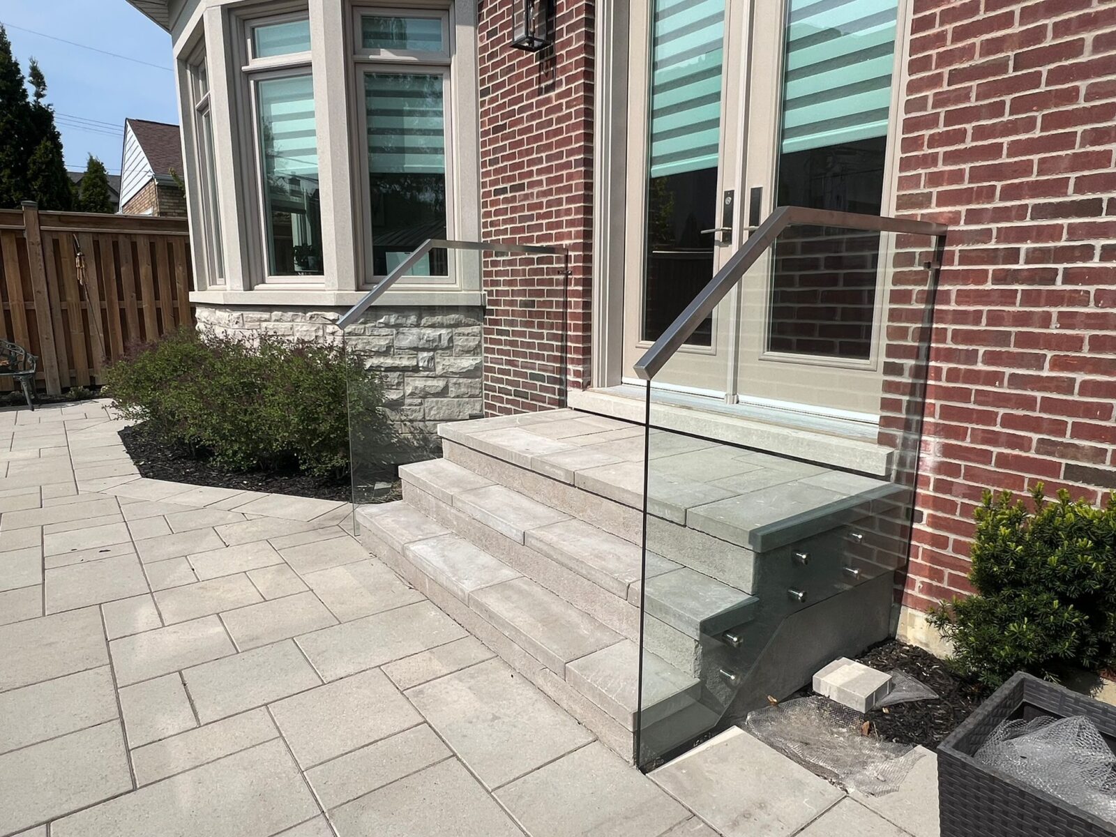 alt="Modern frameless glass railing on front porch installed to match staircase glass handrail in Toronto"