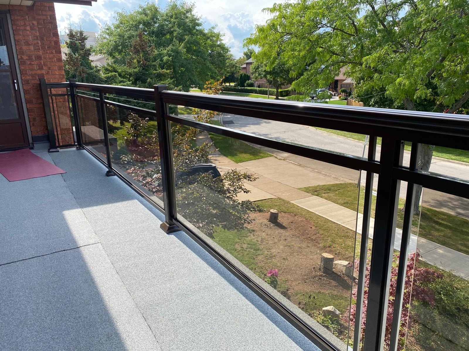 alt="Aluminum and glass railings Toronto with bronze-tinted glass panels installed on a modern balcony"
