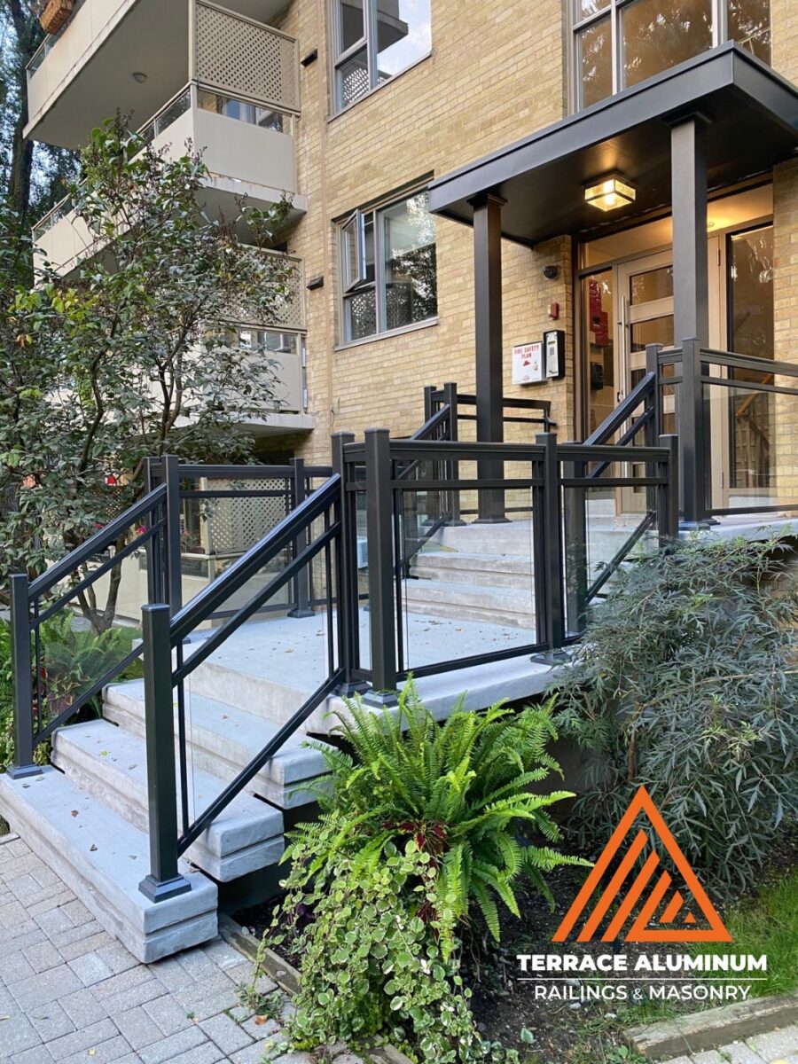 alt="Aluminum and glass railing installed at the front entrance of a Toronto condo by Terrace Aluminum Railings, featuring clear tempered glass panels and powder-coated aluminum posts for a sleek professional look."