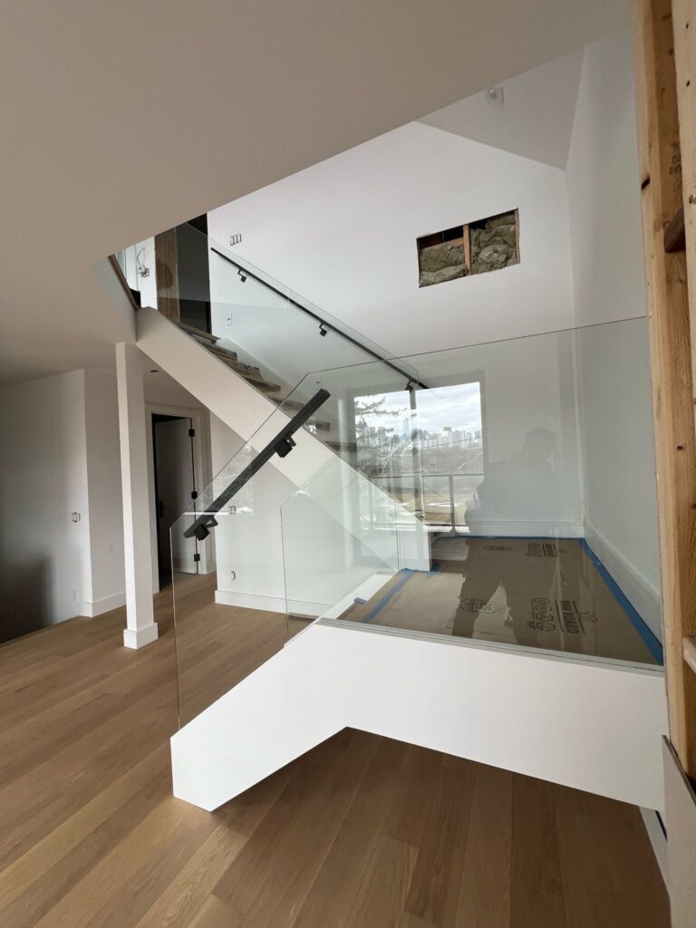 alt="Interior glass railings Toronto with frameless glass railings along an open-concept staircase in a modern home"