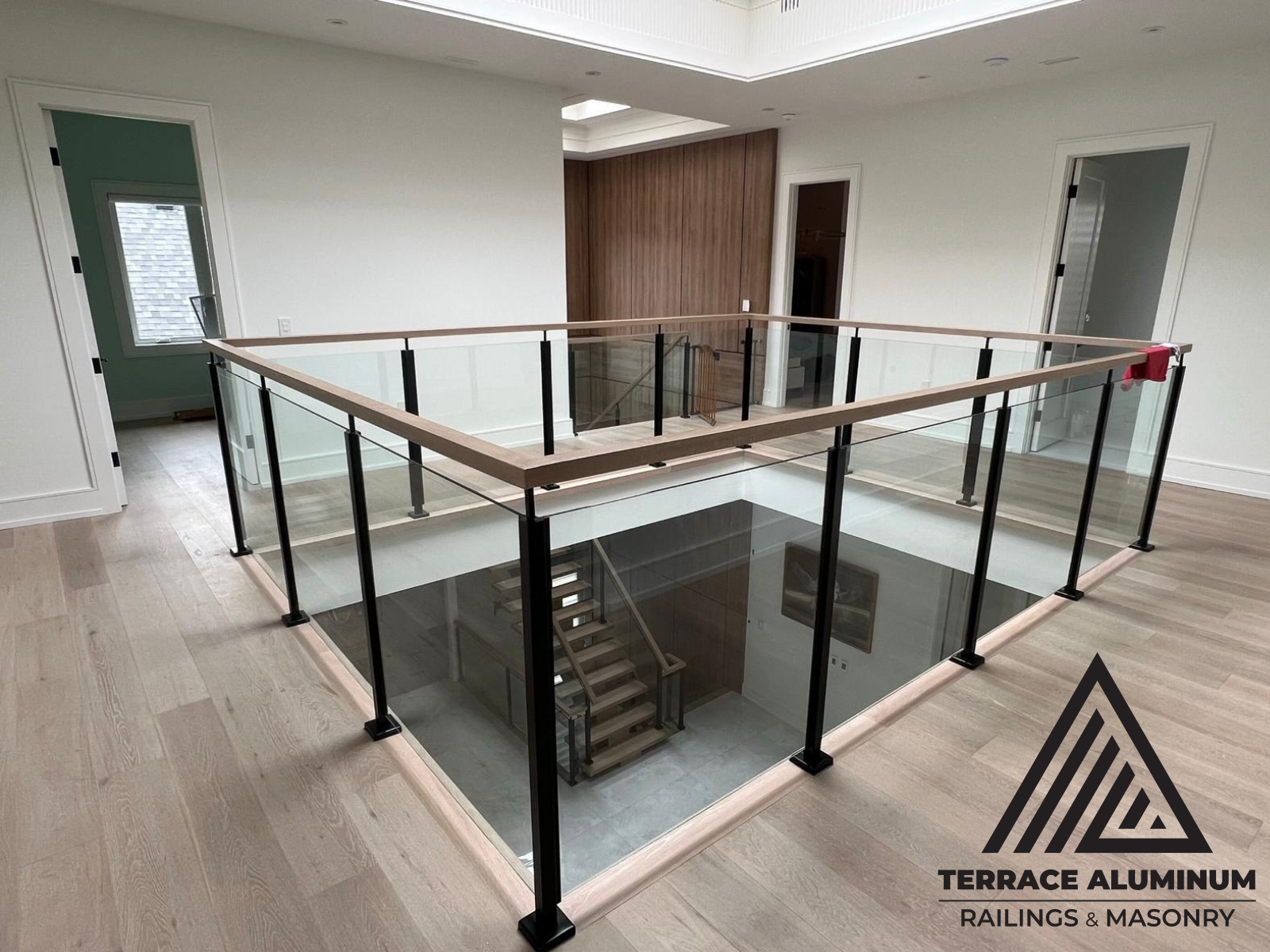 alt="Interior glass railing installation in Toronto by Terrace Aluminum Railings, featuring 12mm clear tempered glass panels and stainless steel posts for a modern indoor staircase."