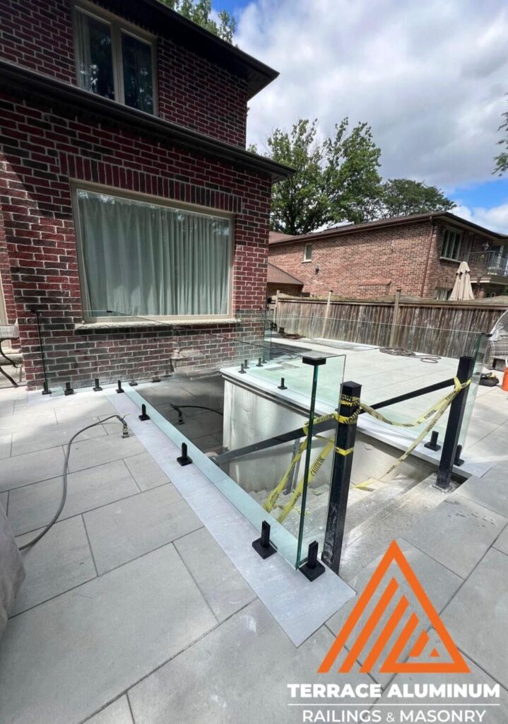 Frameless exterior glass railings installed on a Oakville deck by Terrace Aluminum Railings & Masonry, featuring 12mm clear tempered glass panels and stainless steel spigots.