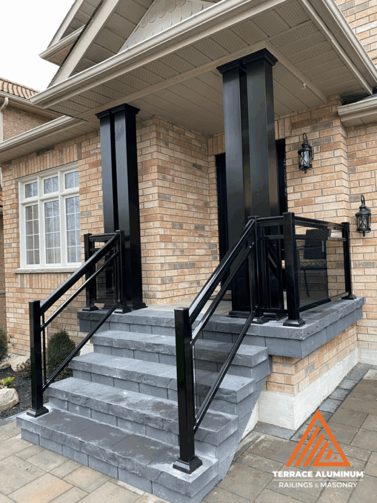 Framed aluminum and glass railings on a Oakville front porch installed by Terrace Aluminum Railings & Masonry, featuring 6mm clear tempered glass and powder-coated aluminum posts.
