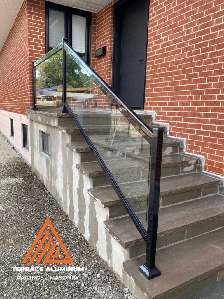 Aluminum framed glass railing on a flagstone front porch in Oakville with clear tempered glass.
