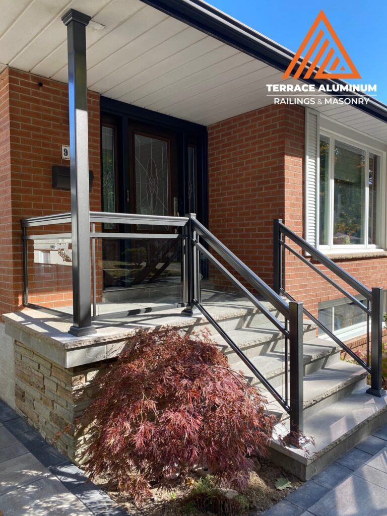 Aluminum and glass railings on a flagstone porch in Oakville installed by Terrace Aluminum Railings & Masonry, featuring clear tempered glass panels and black aluminum posts.