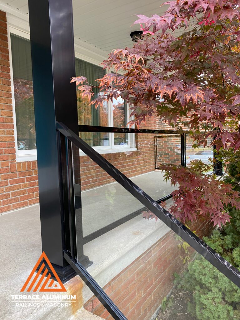Aluminum and glass porch railing with clear tempered glass panels installed on a front porch in Oakville, Ontario.
