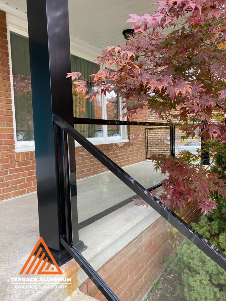 Framed aluminum and glass railing installed on a porch in Oakville with clear tempered glass panels.