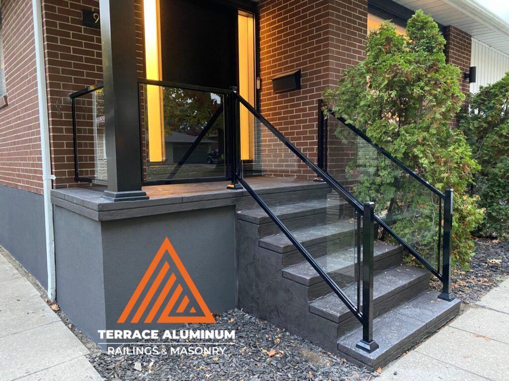 Glass porch railing installed on a front porch in Oakville with clear tempered glass and aluminum posts.