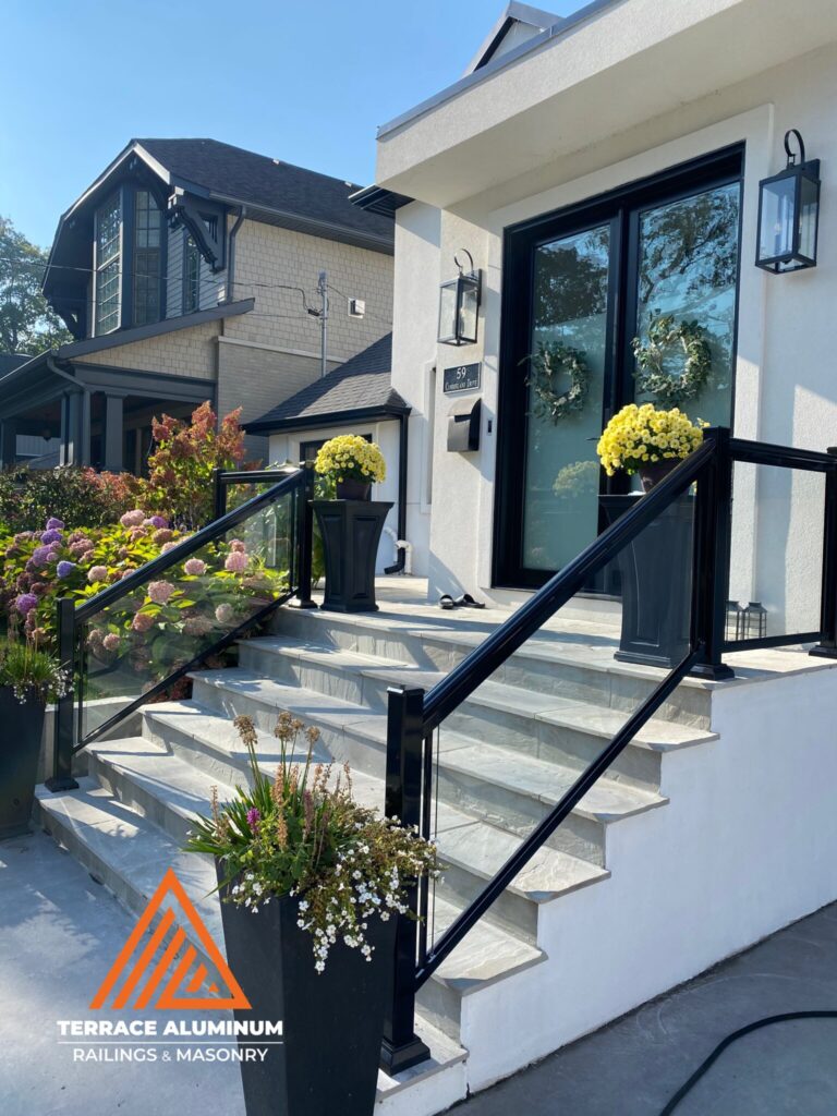 Glass porch railing installed on a flagstone front porch in Oakville with clear tempered glass panels.