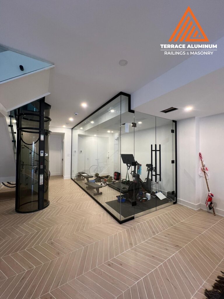 Glass wall with black framing in basement gym Oakville — interior glass partition by Terrace Aluminum Railings & Masonry