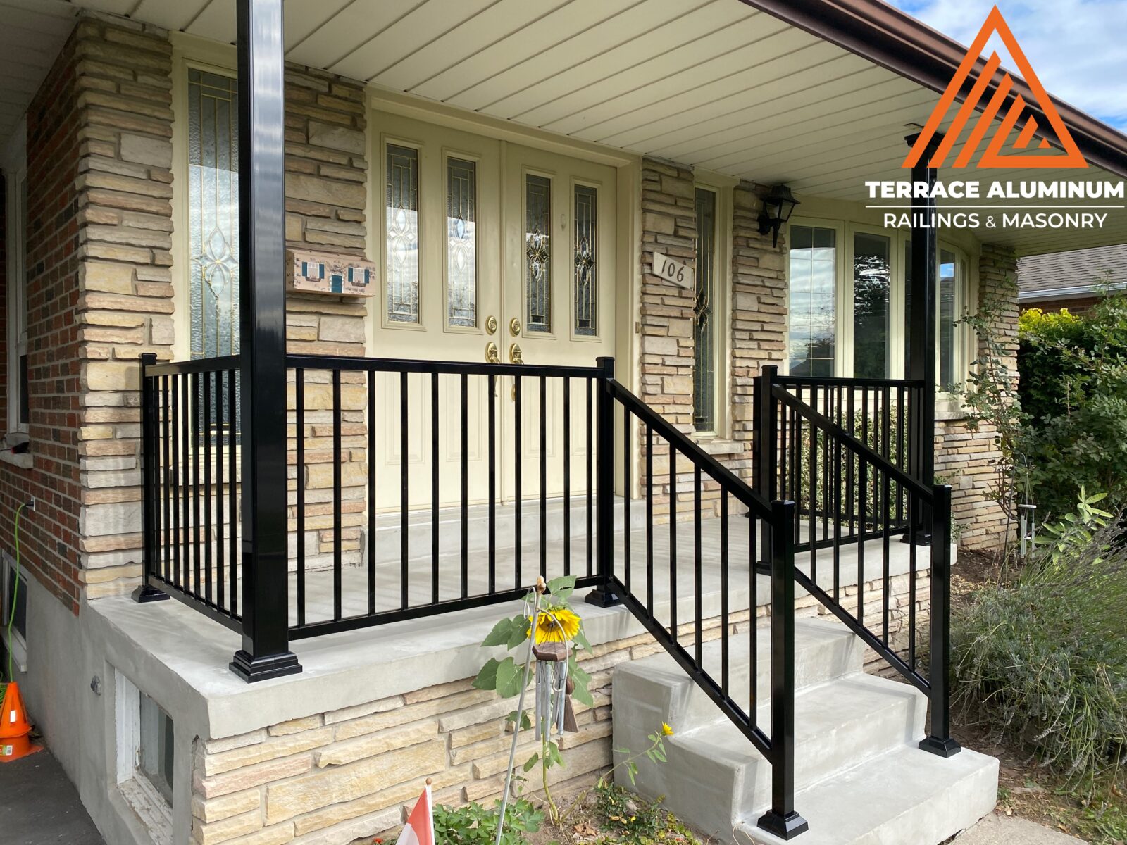 Black aluminum railing installed on a front porch, showing a durable and low-maintenance exterior railing system