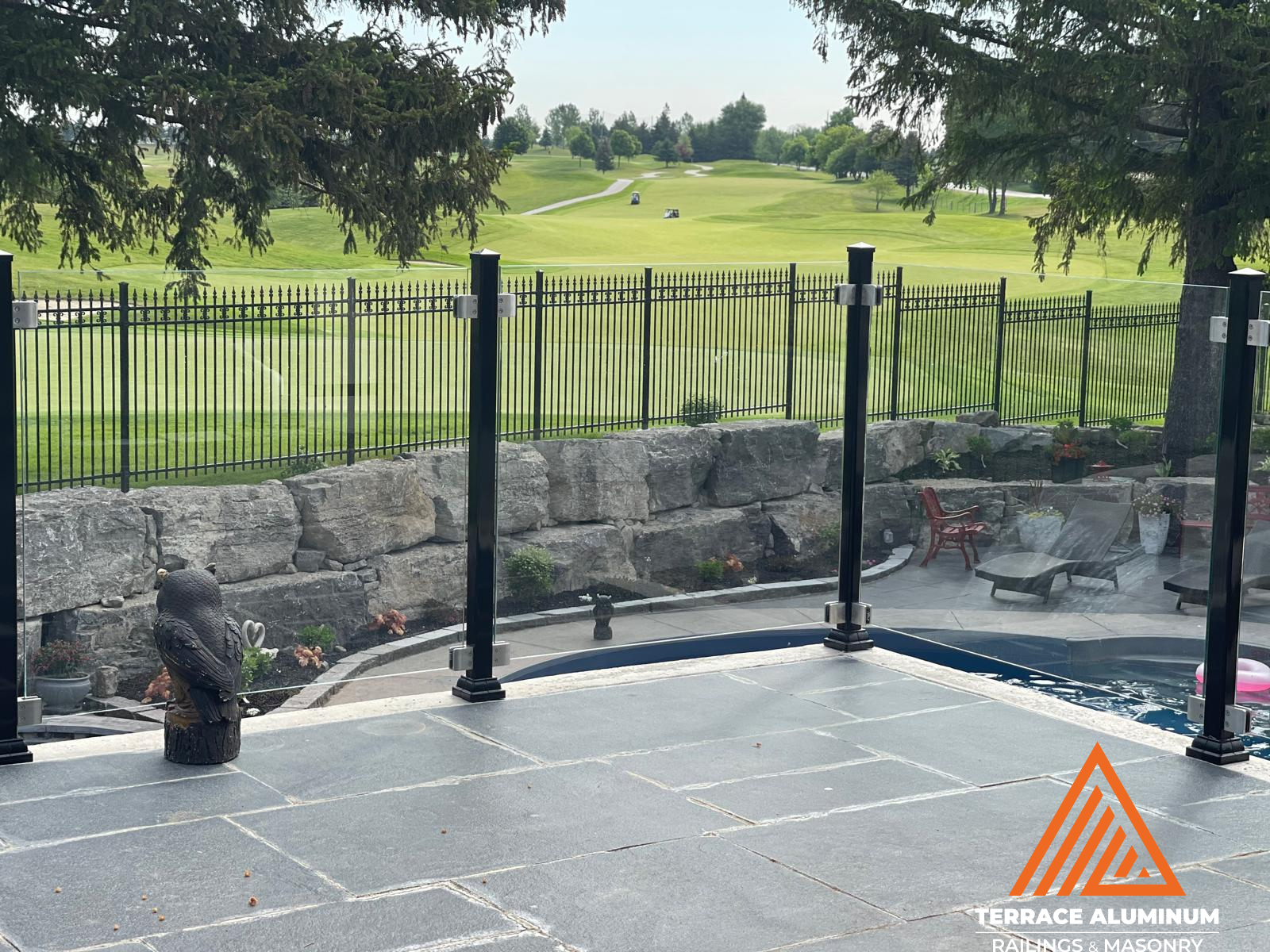 Frameless glass railing by a pool in Hamilton with aluminum posts installed by Terrace Aluminum Railings, featuring 12mm tempered glass panels for a modern and safe pool enclosure."