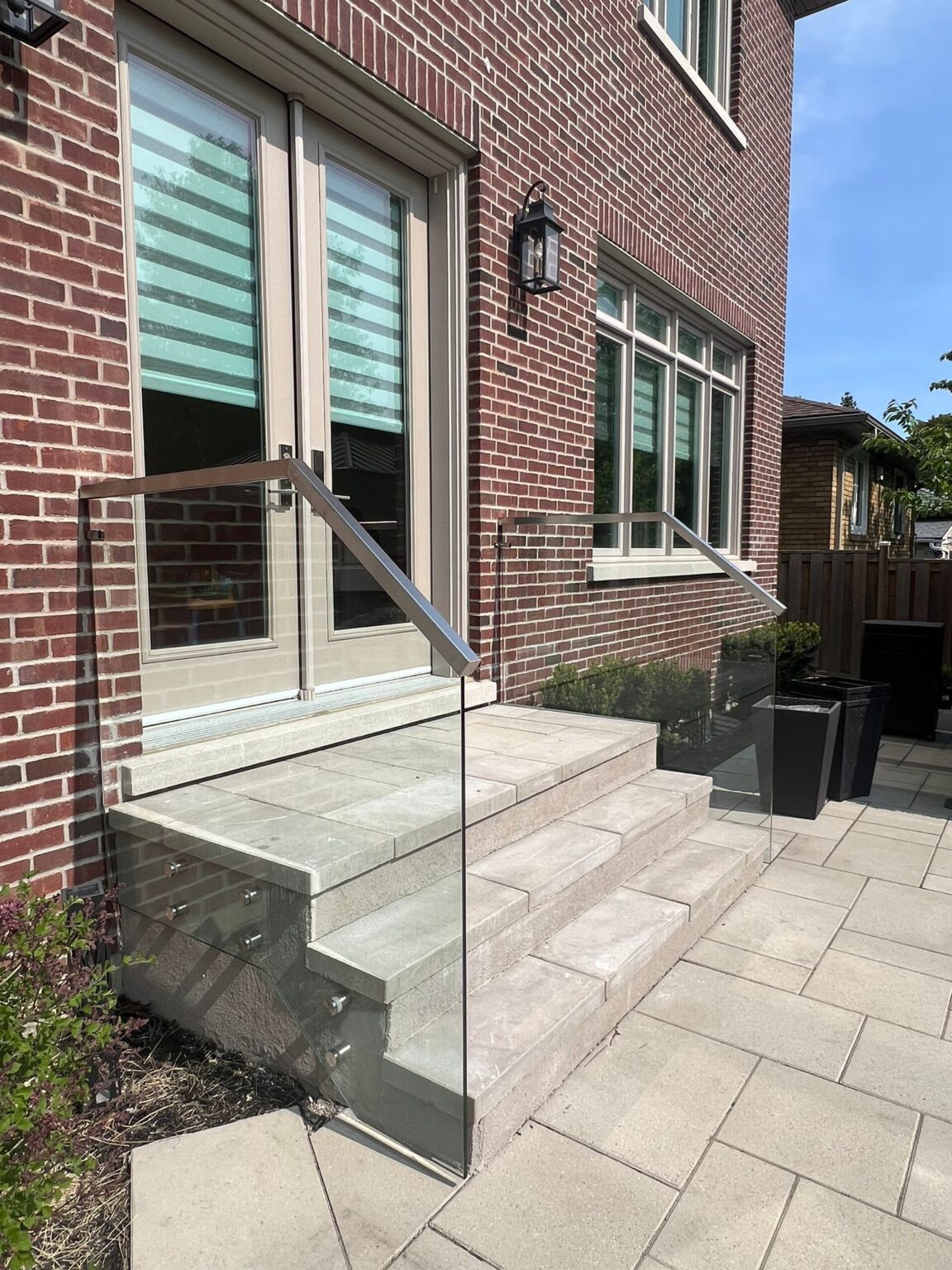 Frameless glass railing installation on a Hamilton front porch by Terrace Aluminum Railings, featuring clear 12mm tempered glass panels for a high-end modern finish.