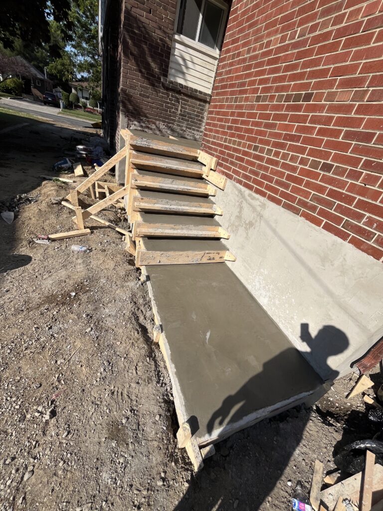 A reinforced concrete side staircase and walkway provide the strong foundation for a durable, long-lasting hardscaping installation