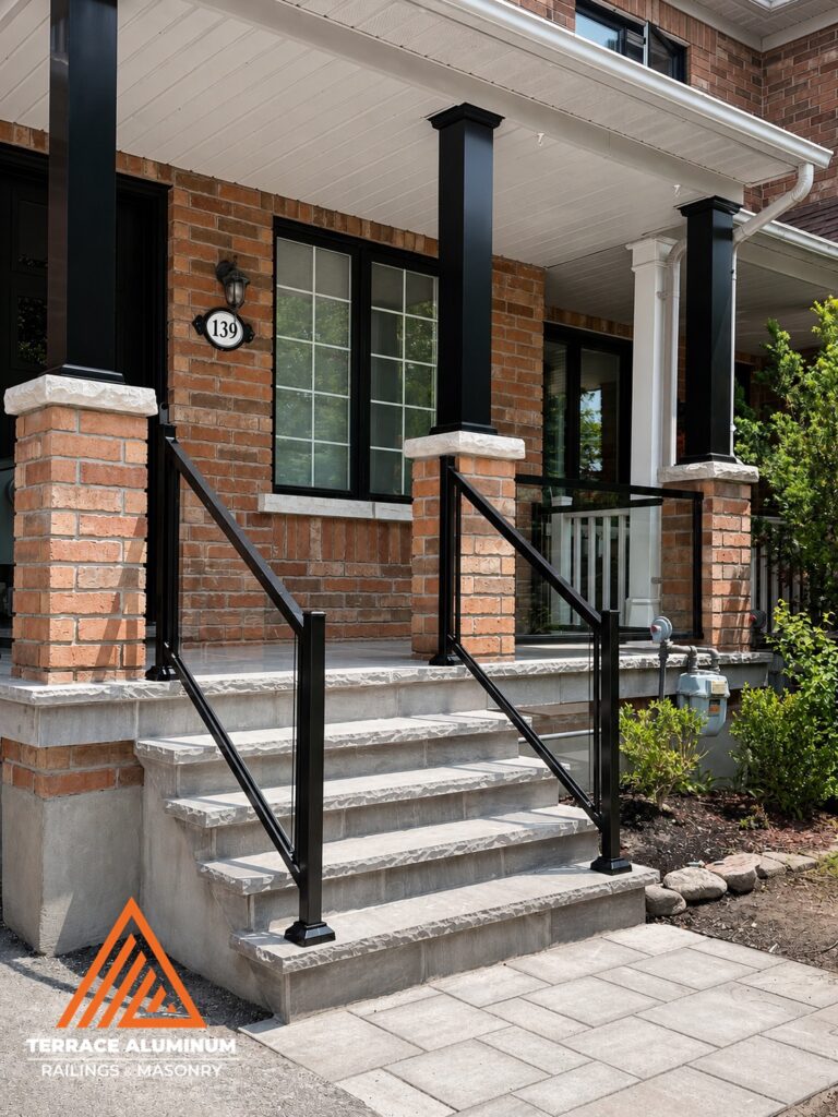 Flagstone front porch with interlock walkway and glass railing installed by Terrace Aluminum Railings and Masonry.