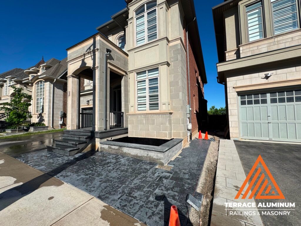 Front yard with Black Pearl flagstone coping, interlocking pavers, garden beds, and river rock as part of a Hardscaping Oakville project