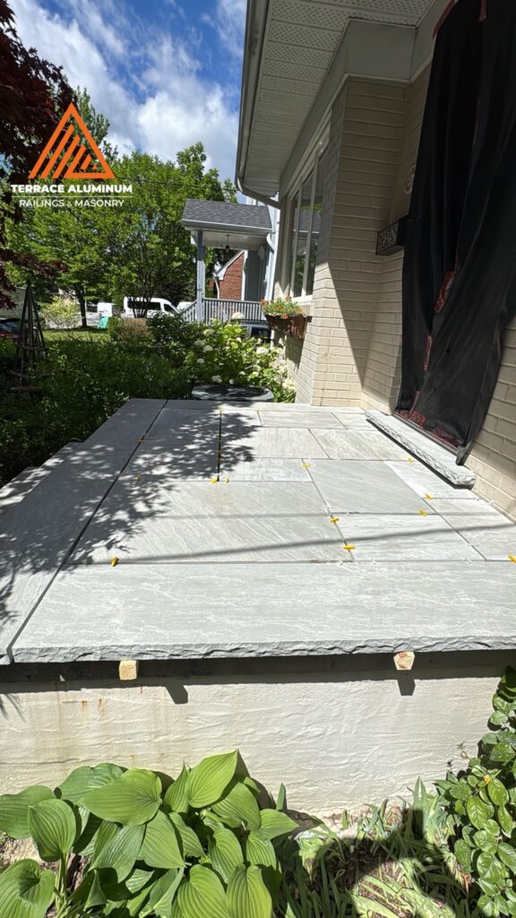 Flagstone laid on a front porch and ready for grout for hardscaping services in Etobicoke.