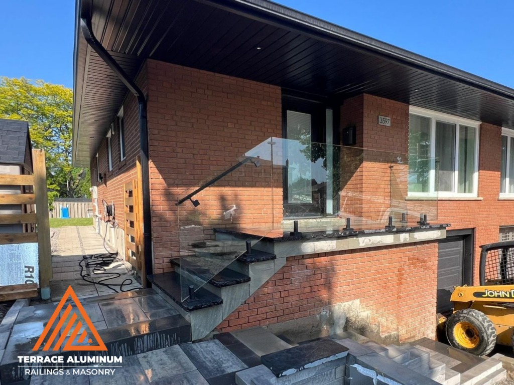 Flagstone porch with an interlock walkway and frameless glass railing for hardscaping services in Etobicoke.